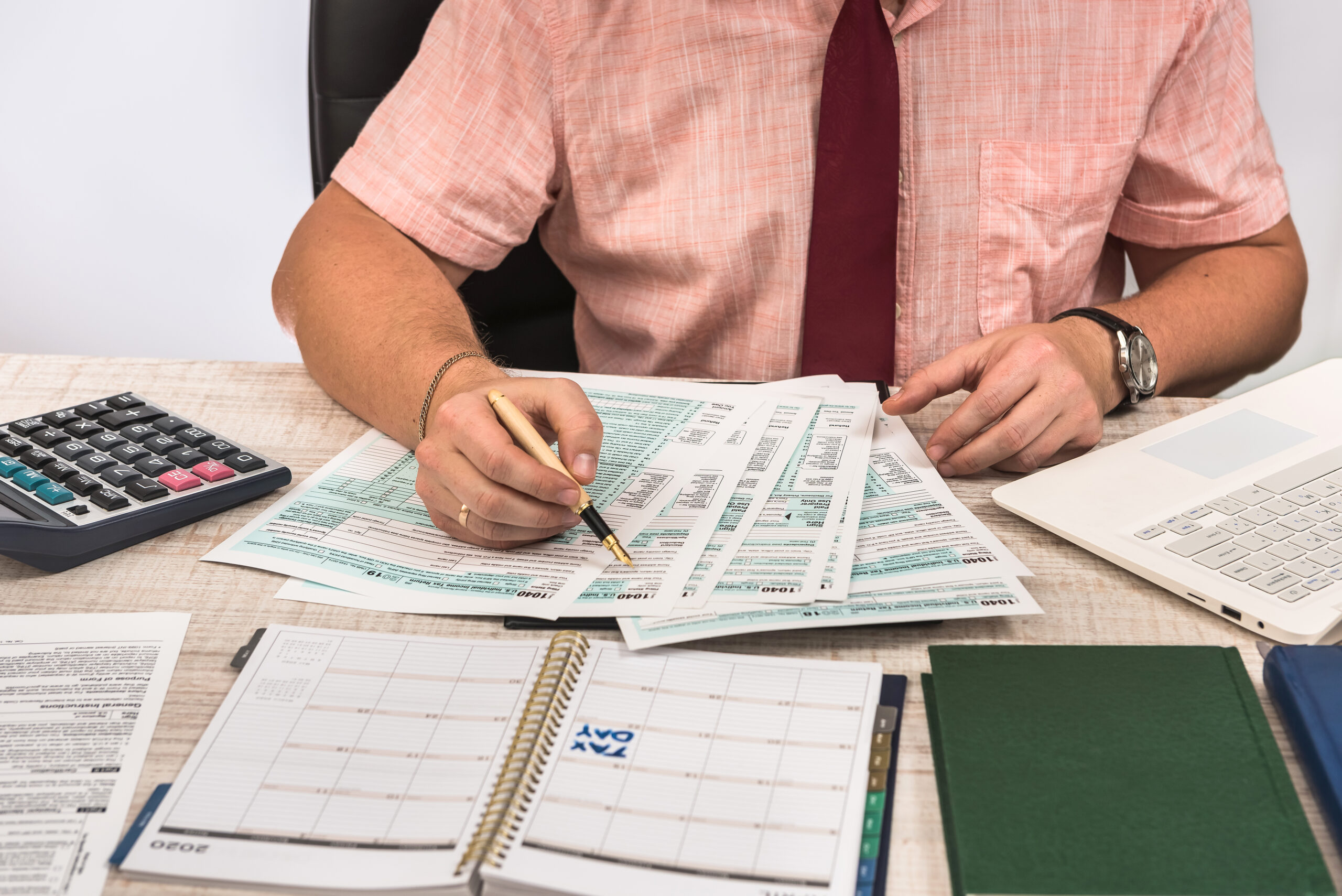 Unternehmer füllt Steuerformular mit Taschenrechner aus – Jahresabschlüsse & Steuererklärungen